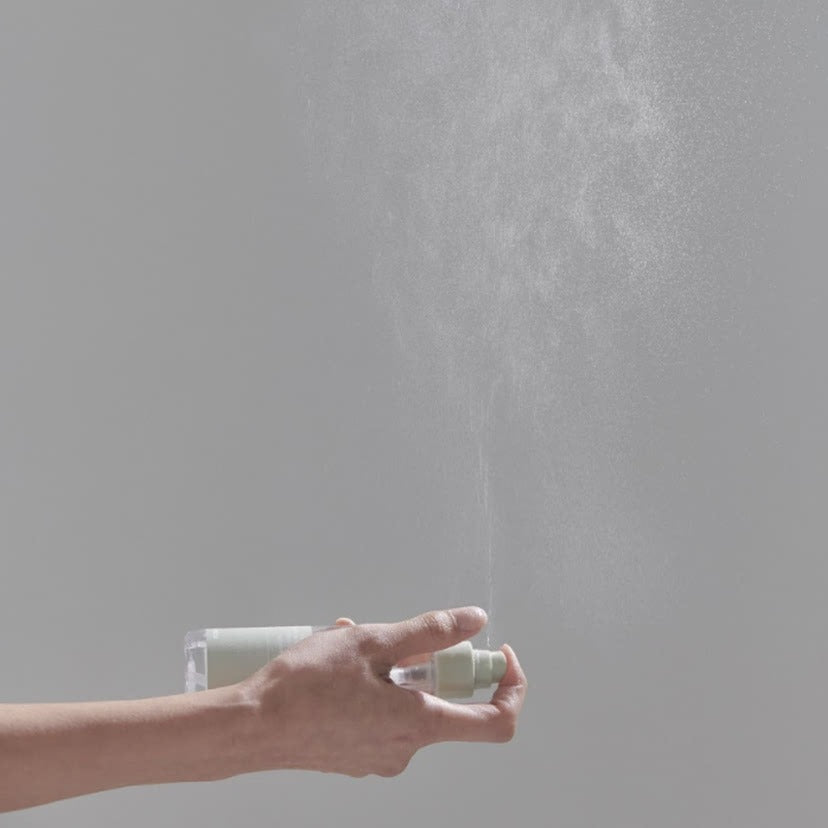 CELIMAX Ji Woo Gae Heartleaf BHA Body Mist 150ml : main en spray, flacon en arrière-plan sur fond gris clair.