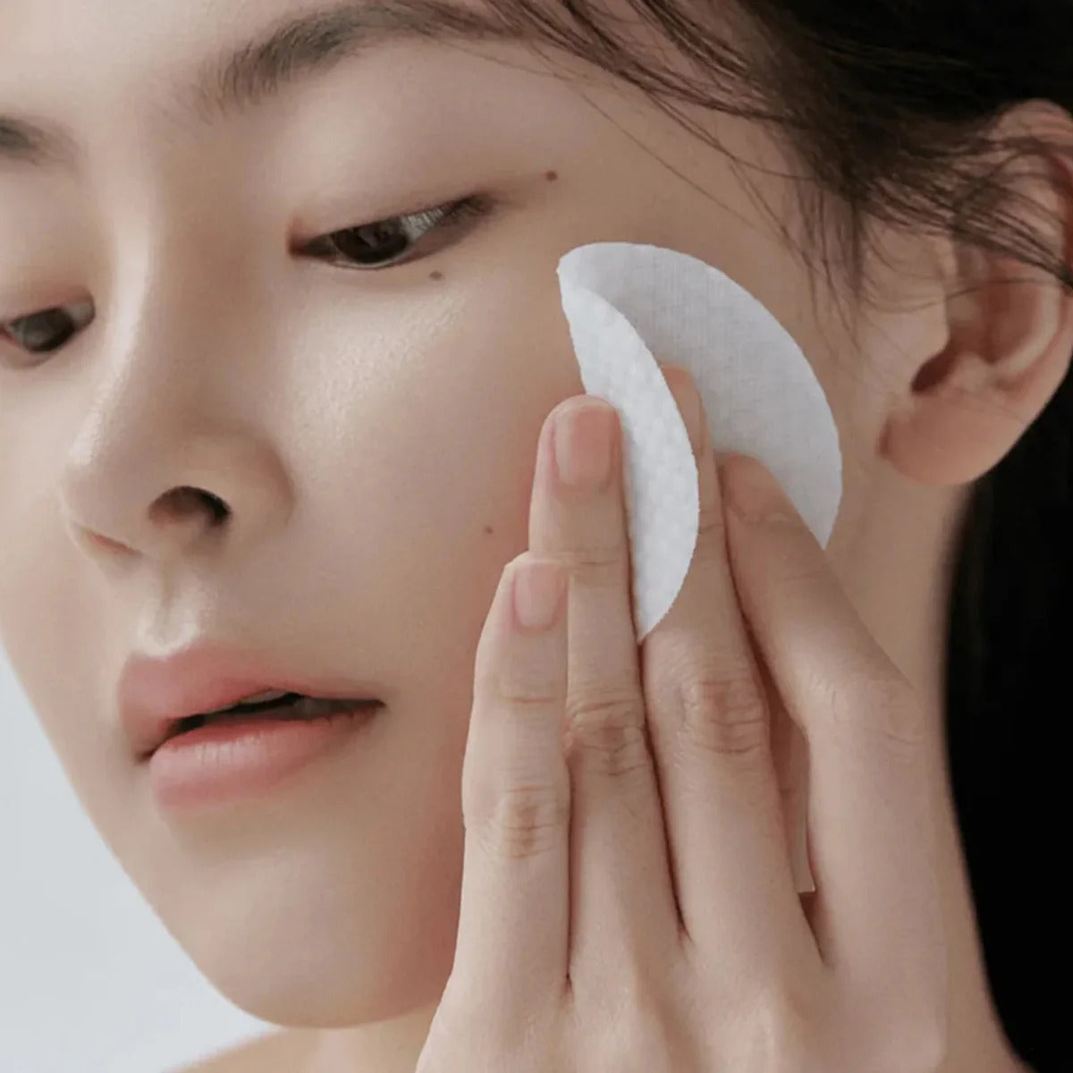 CELIMAX Ji Woo Gae Heartleaf BHA Peeling Pad 60 Pads: femme applique un pad blanc sur la peau du visage, marque CELIMAX