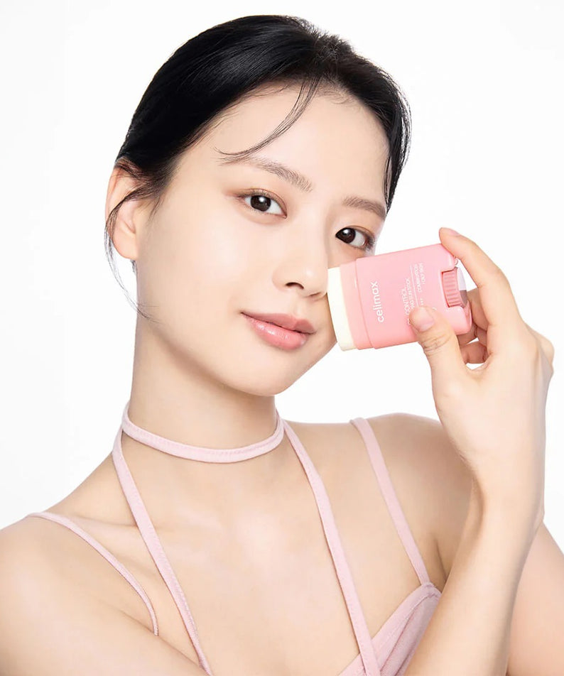 CELIMAX Oil Control Sun Stickk 19g, femme applique un stick solaire anti-brillance rose sur fond clair.