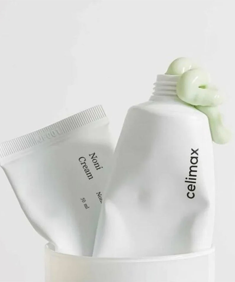 CELIMAX The Real Noni Energy Repair Cream 50ml, tube et pot sur fond clair avec feuilles de noni, marque CELIMAX