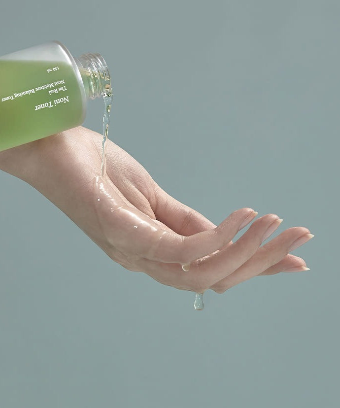 CELIMAX The Real Noni Moisture Balancing Toner 150ml, main avec peau hydratée, flacon vert, soin visage