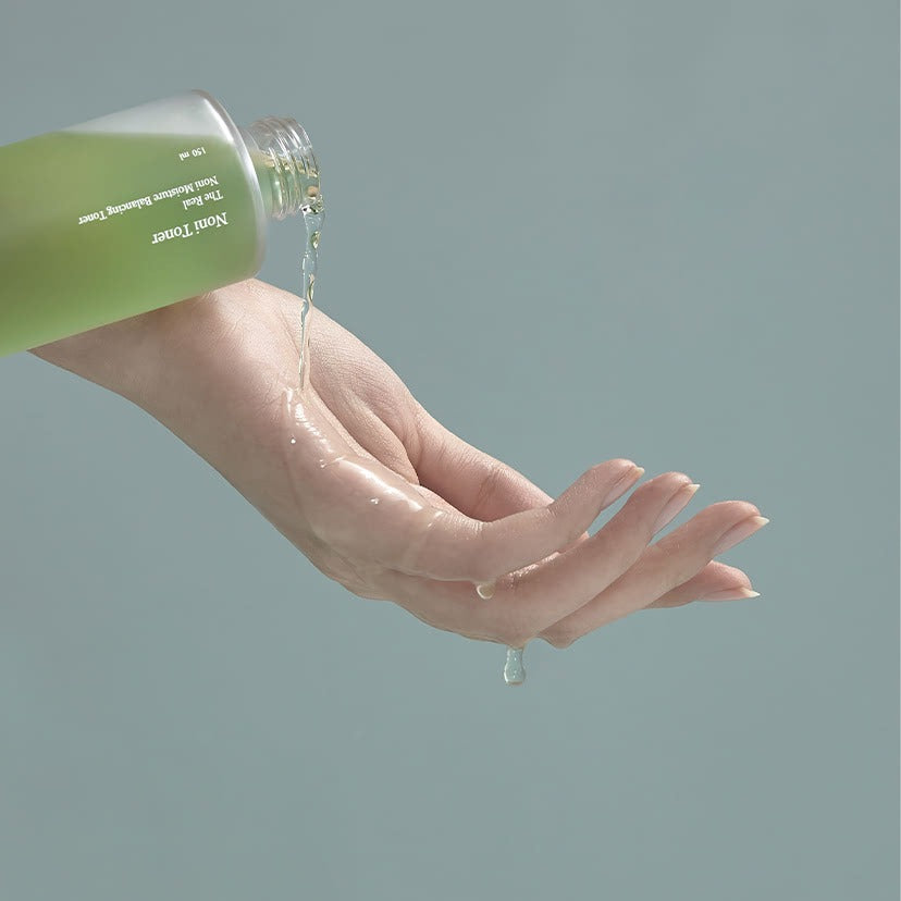 CELIMAX The Real Noni Moisture Balancing Toner 150ml, main avec peau hydratée, flacon vert, soin visage