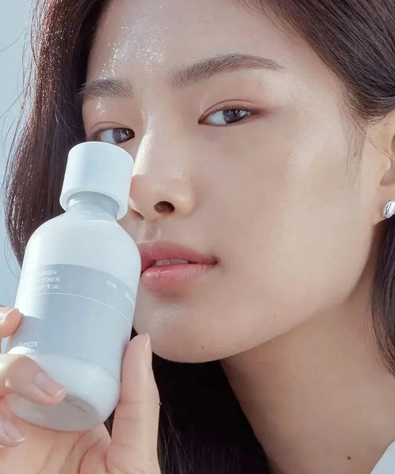 Femme tenant le CELIMAX Dual Barrier Creamy Toner 150ml près de son visage, montrant la texture du produit.