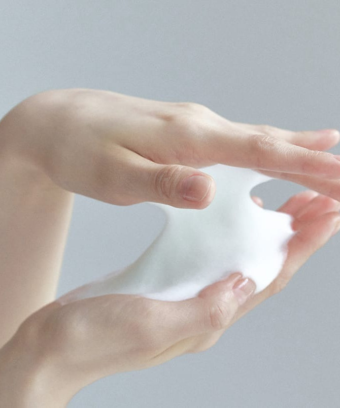 Mains tenant de la mousse du CELIMAX The Real Noni Acne Bubble Cleanser 155ml pour une peau nettoyée et purifiée.