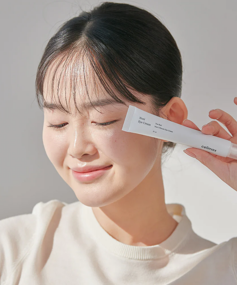 Femme souriante tenant CELIMAX The Real Noni Ultimate Eye Cream 20ml, soin contour des yeux efficace et nourrissant.
