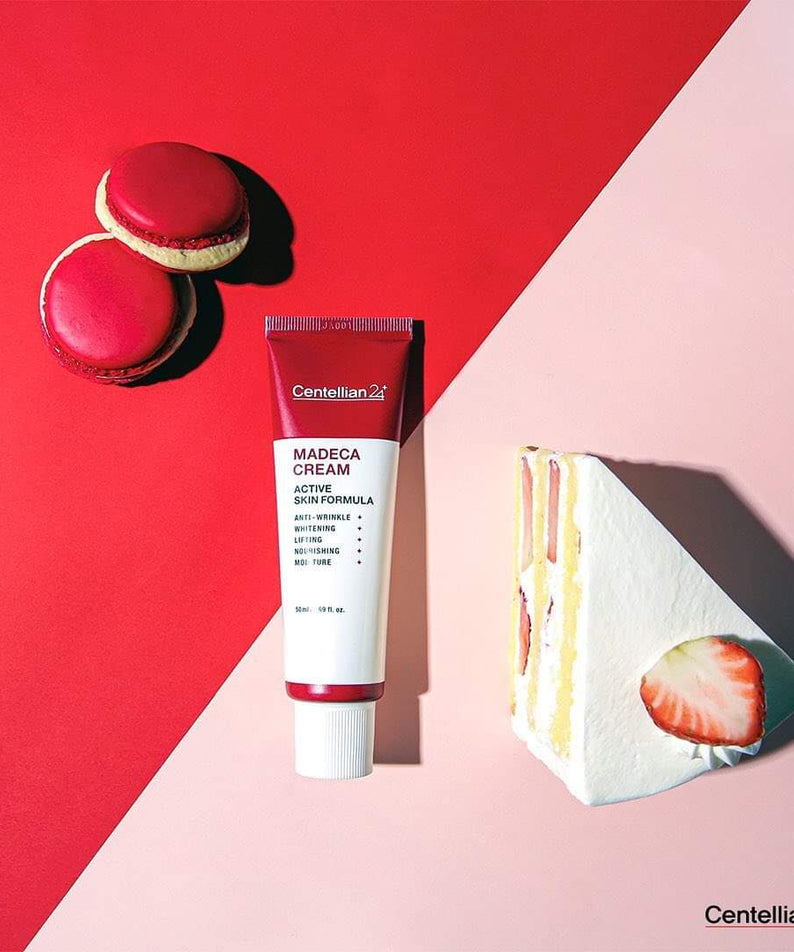 CENTELLIAN 24 Madeca Cream Active Skin Formula 50ml sur fond rouge avec macarons et gâteau aux fraises à côté.
