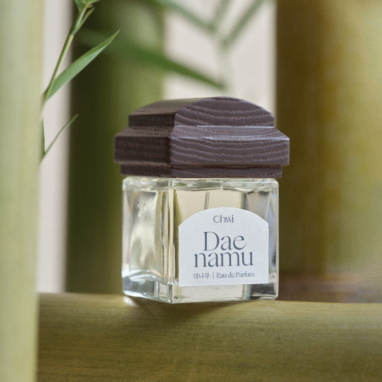 CHWI (CHI) Eau De Parfume 50ml, flacon Dae Mamu sur table, ambiance verte naturelle, marque visible, intérieur lumineux.
