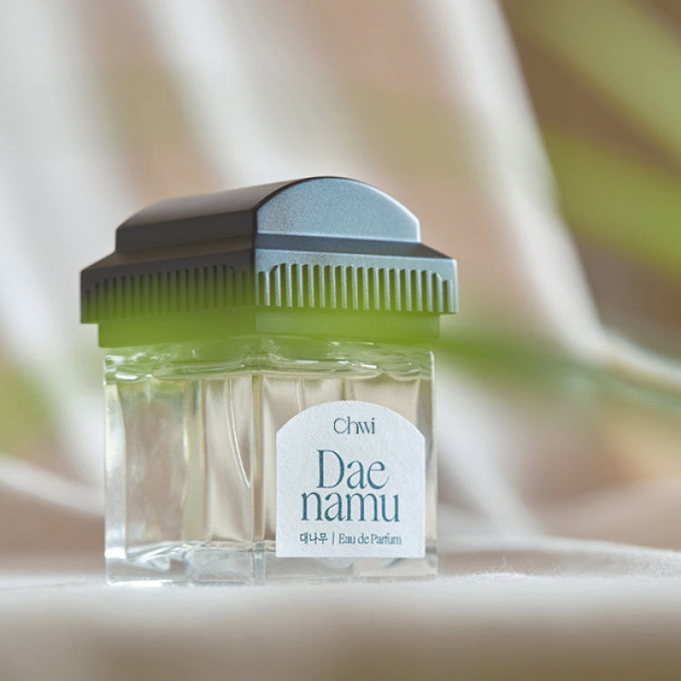 CHWI (CHI) Eau De Parfume 50ml, flacon vert sur tissu clair, étiquette visible, ambiance douce et lumineuse