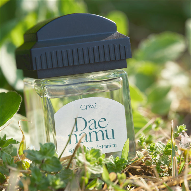 CHWI (CHI) Eau De Parfume 50ml de la marque CHWI en flacon verre vert, sur un fond de feuilles vertes (nature).