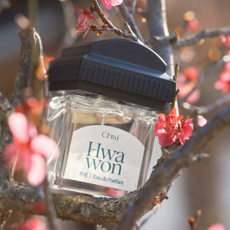 CHWI (CHI) Hwa Won Parfume 50ml, flacon sur branche fleurie, marque CHWI, contexte printanier en extérieur.
