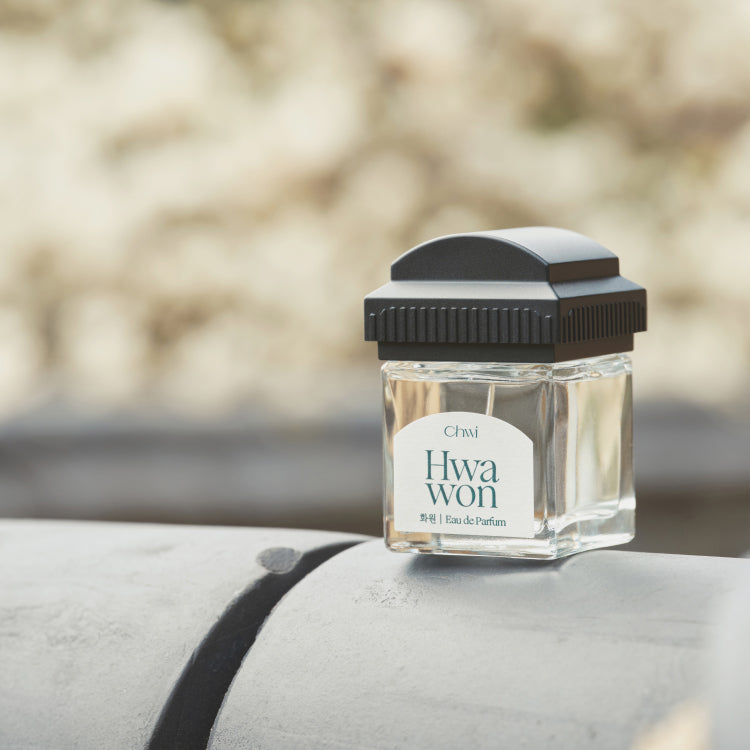 CHWI (CHI) Hwa Won Parfume 50ml, flacon noir et verre posé sur banc, ambiance extérieure floue, marque CHWI