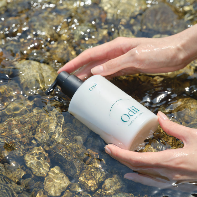 CHWI (CHI) Odii Hand & Body Lotion 300ml : flacon appliqué sur les mains au bord de l’eau, marque CHI