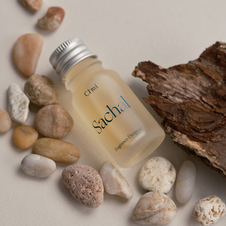 CHWI (CHI) Sachak Fraangrance Dropper 10ml de marque CHWI, flacon avec pierres et bois sur fond clair.
