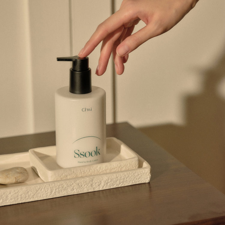 CHWI (CHI) Ssook Hand & Body Lotion 300ml sur présentoir, main pompe; produit CHI en salle de bain, contexte visuel.