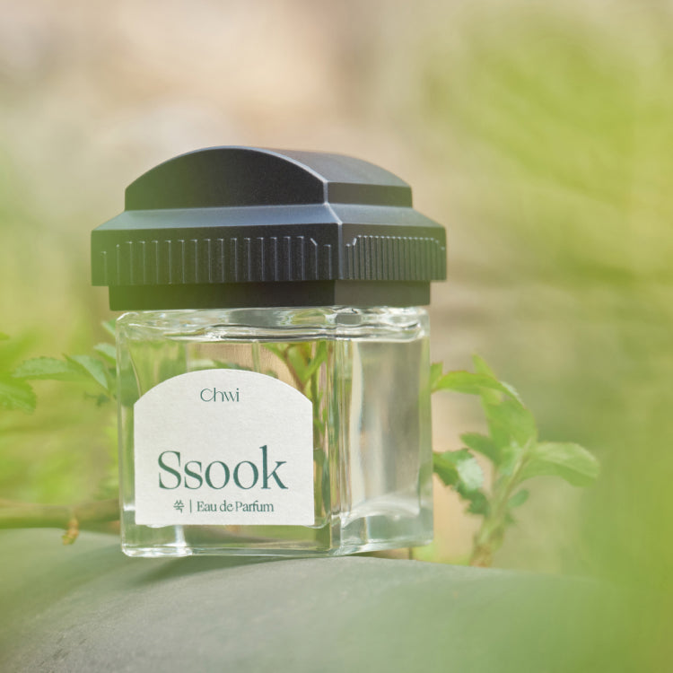 CHWI (CHI) Ssook Parfume 50ml, flacon vert sur fond nature floue, marque CHWI visible, ambiance fraîche en extérieur.