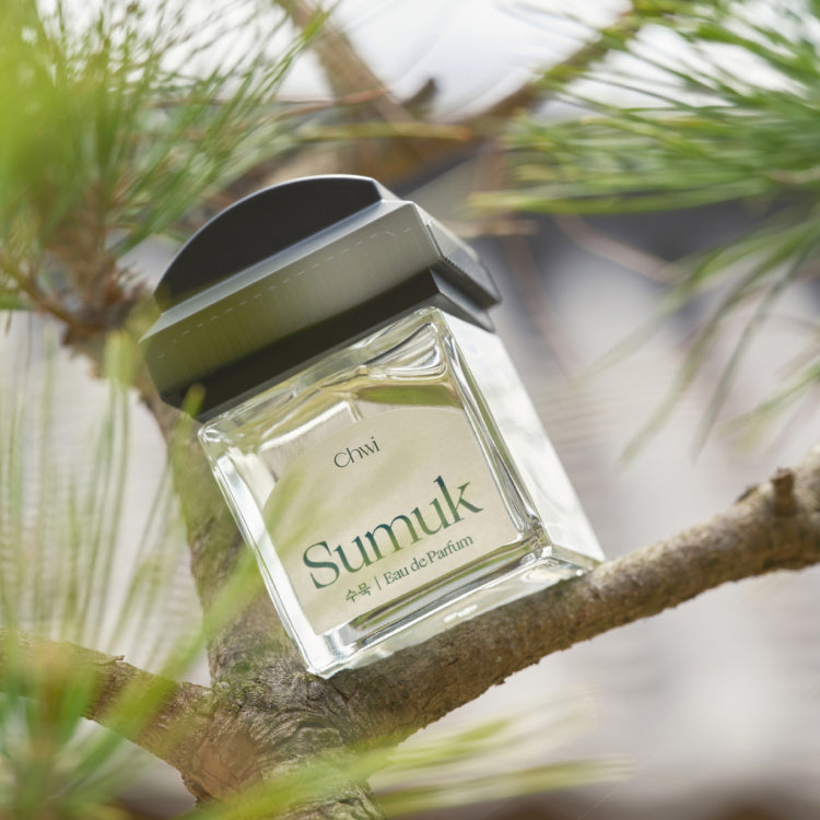 CHWI (CHI) Sumuk Parfume 50ml sur branche, flacon vert, marque CHI, décor tropical avec feuilles et lumière naturelle