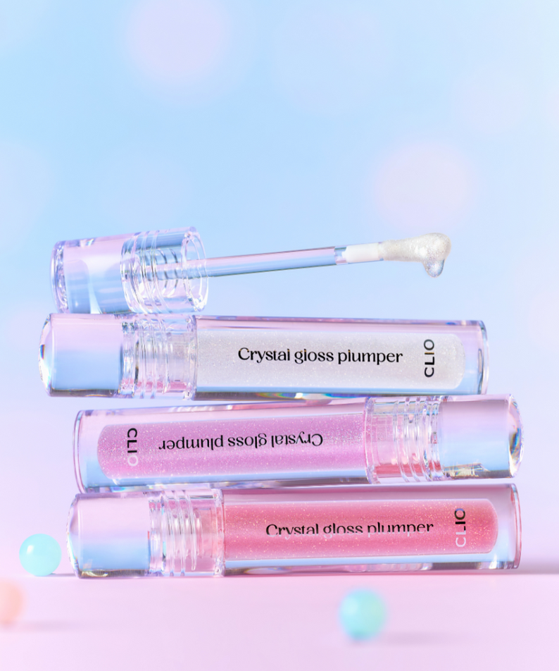 Gamme CLIO Crystal Gloss Plumper sur fond pastel rose et bleu, accentuant la brillance et le volume des lèvres. Rouge à lèvres gloss.