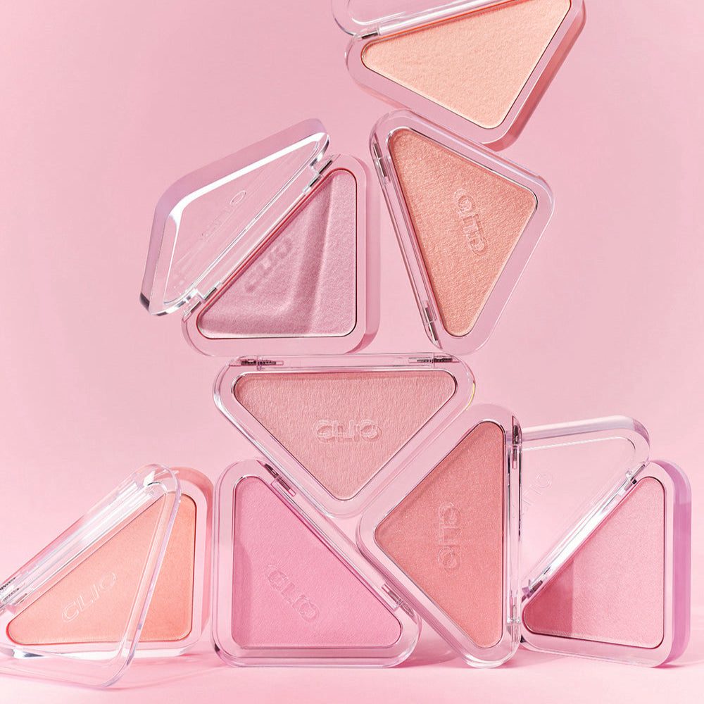 CLIO  Essential Blush Tab, poudres blush roses en étui triangle sur fond rose pastel, packshot de la marque CLIO.