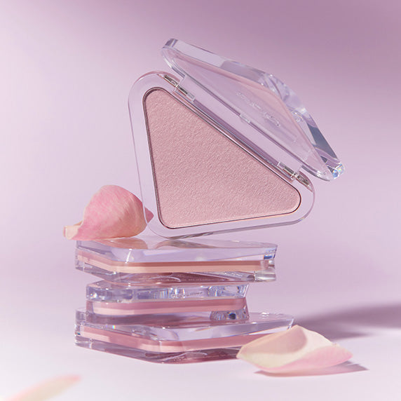 CLIO  Essential Blush Tab de CLIO, poudrier en verre ouvert avec blush rose sur fond pastel.
