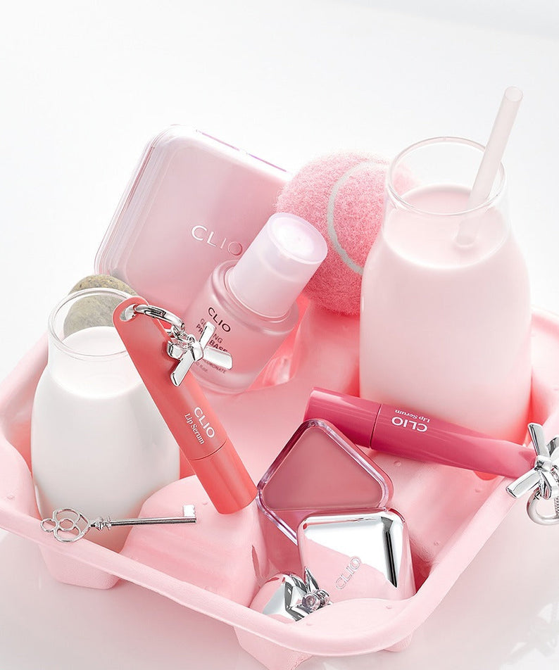 CLIO Glazing Prep Base 40ml de CLIO en flacon rose sur kit maquillage, contexte visuel studio blanc et rose