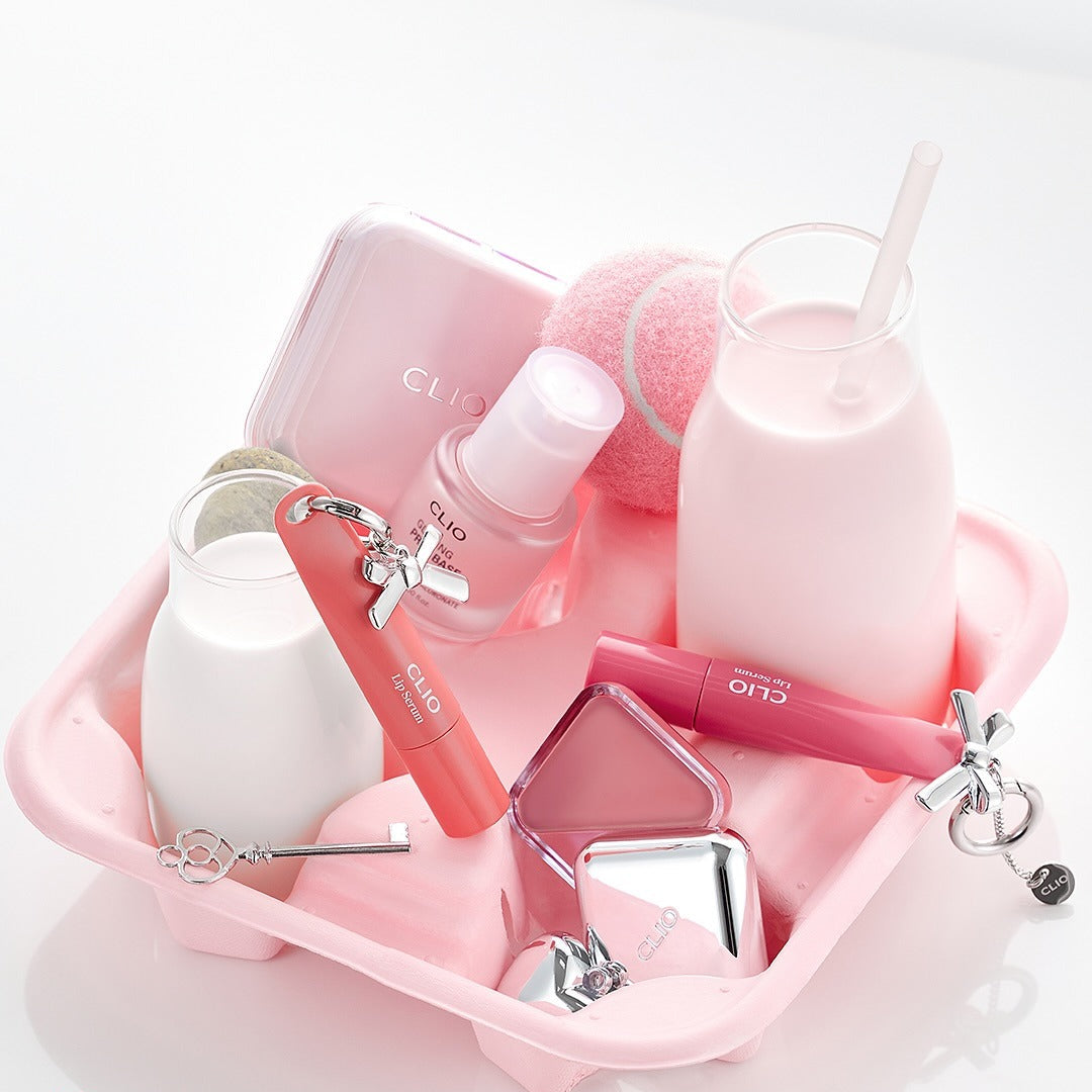 CLIO Glazing Prep Base 40ml de CLIO en flacon rose sur kit maquillage, contexte visuel studio blanc et rose