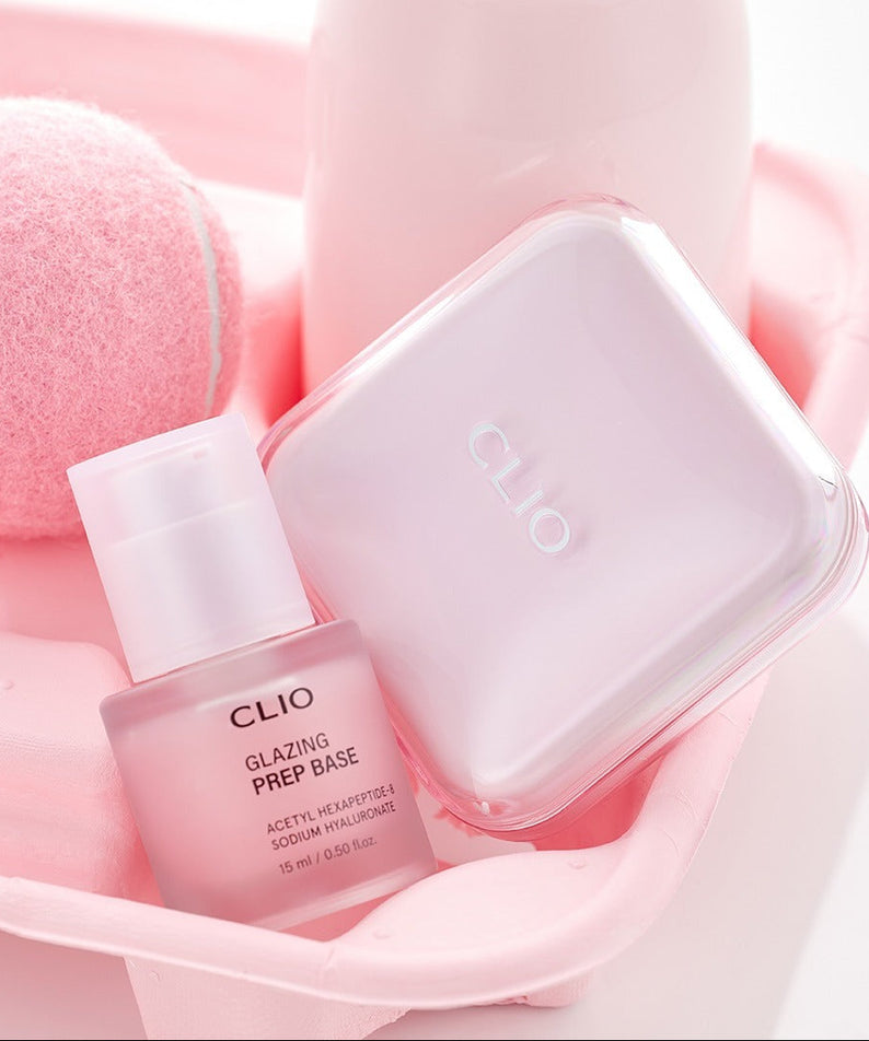 Décris l'image en français : CLIO Glazing Prep Base 40ml de CLIO, flacon rose sur accessoires de manucure, gros plan.