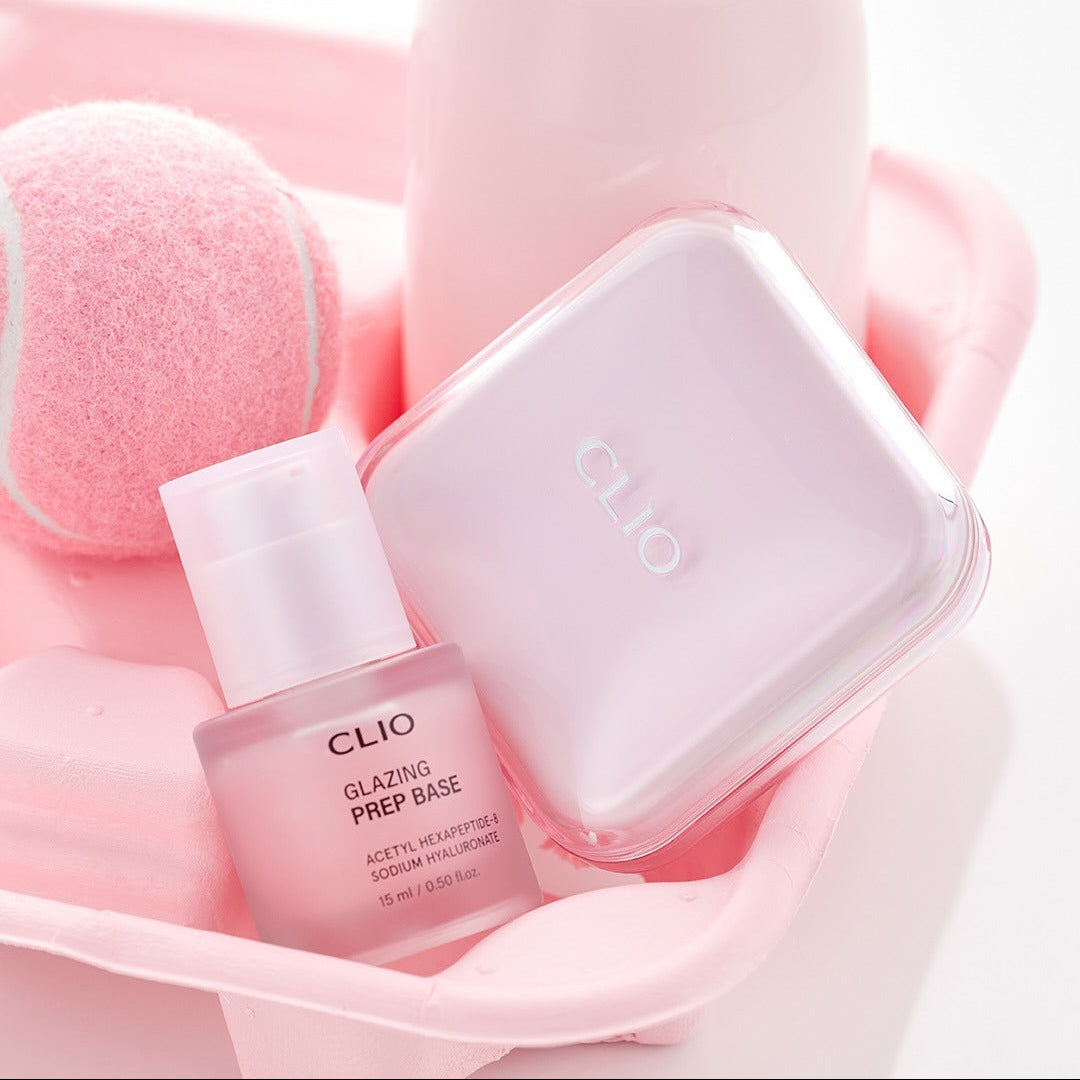 Décris l'image en français : CLIO Glazing Prep Base 40ml de CLIO, flacon rose sur accessoires de manucure, gros plan.