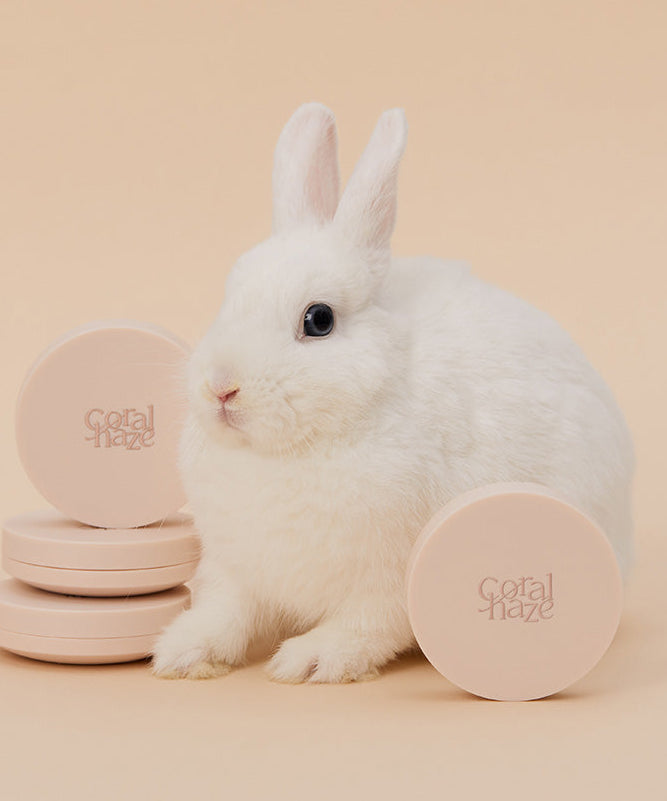 Lapin blanc avec produits CORALHAZE Fixing Blur Cushion SPF50 PA++++ 13g, ambiance douce et naturelle.