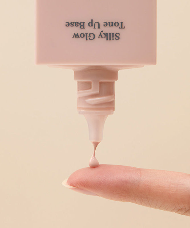 CORALHAZE SIlky Glow Tone Up Base appliqué sur le doigt, montrant la texture crémeuse du produit.