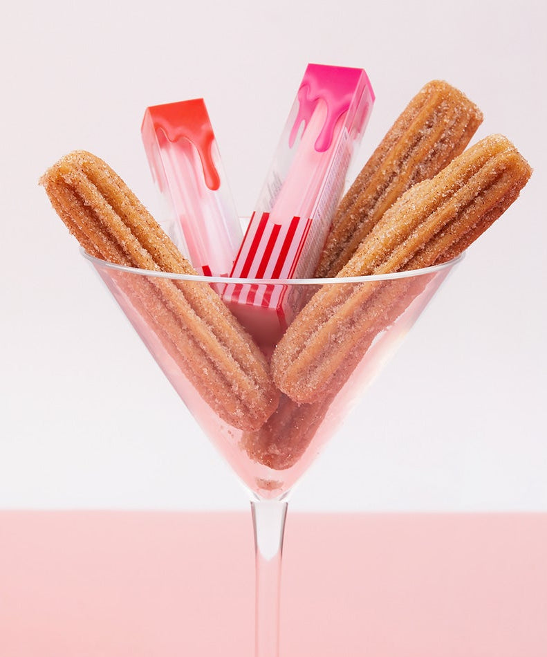 Décris l'image en français : CORINGCO Pink Churrons Plumping Glossy Lip, marque CORINGCO, packaging rose sur fond blanc.