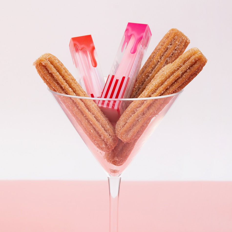 Décris l'image en français : CORINGCO Pink Churrons Plumping Glossy Lip, marque CORINGCO, packaging rose sur fond blanc.