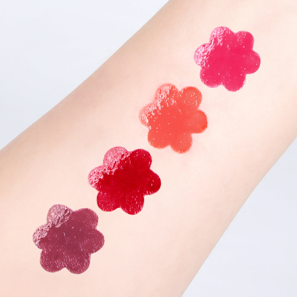 CORINGCO Pink Churrons Plumping Glossy Lip de la marque CORINGCO sur un avant-bras, swatches fleurs roses, fond clair.