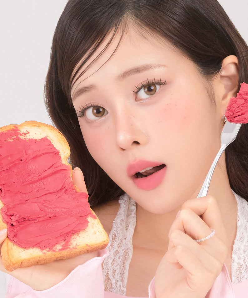 CORINGCO Topping Tip Velvet Lip Tint de CORINGCO : la teinte rose sur lèvres, avec une femme et du pain, fond clair.