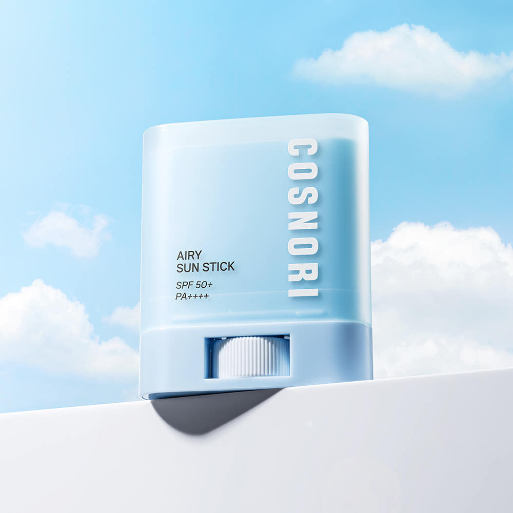 COSNORI Airy Sun Stick 20.5g (SPF50+ PA++++) de la marque COSNORI, sur fond ciel bleu estival, stick sunscreen