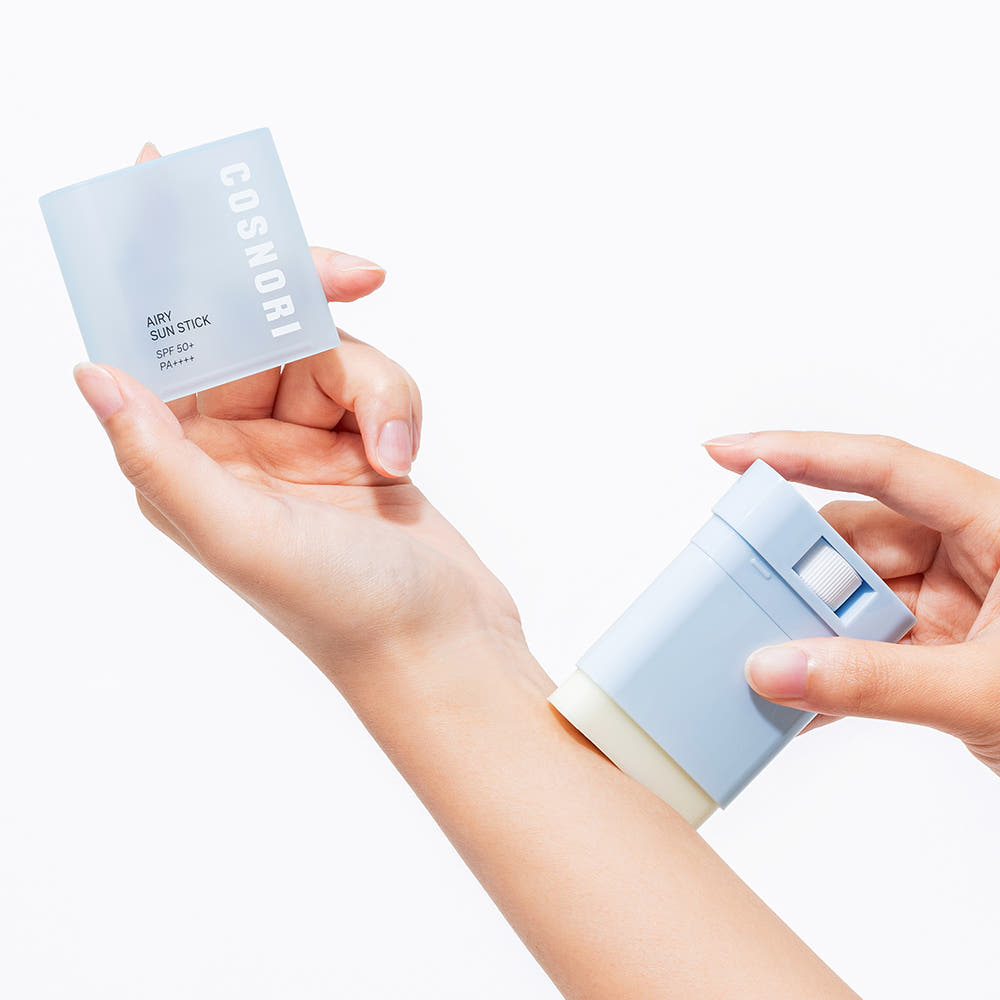 COSNORI Airy Sun Stick 20.5g (SPF50+ PA++++) sur peau, mains appliquant le stick de protection solaire COSNORI