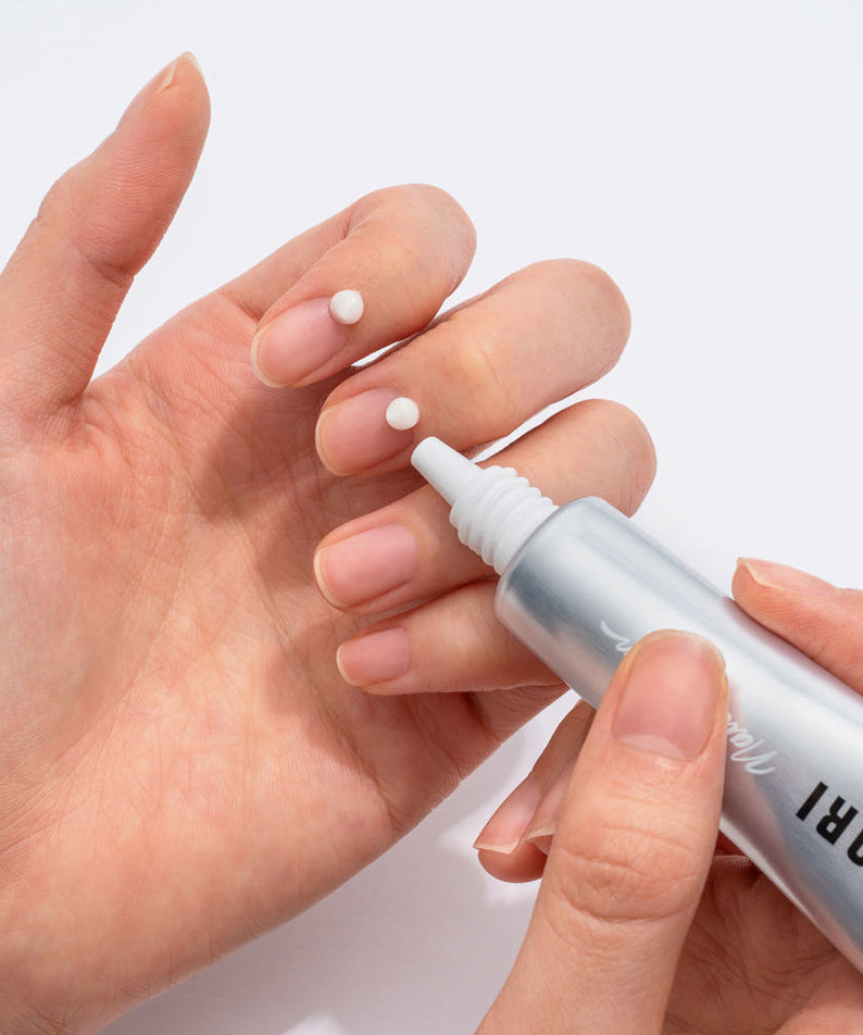COSNORI Nail Nutrition Silk Repair Nail Cream 15ml 2ea, crème réparatrice sur ongles, main appliquant le produit, fond clair.