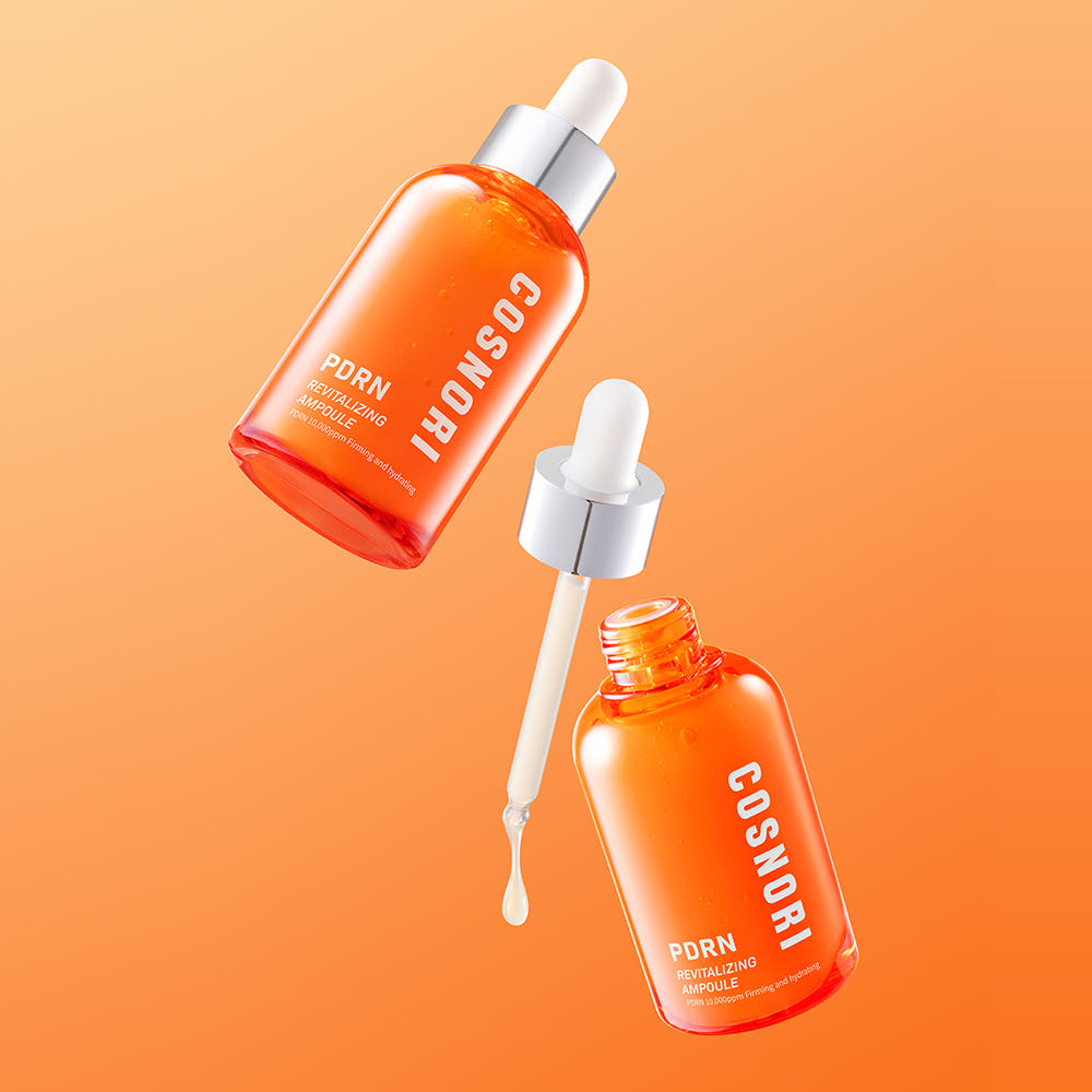 COSNORI PDRN Revitalizing Ampoule 50ml, sérum en flacons orange sur fond orange, gouttes et contexte beauté