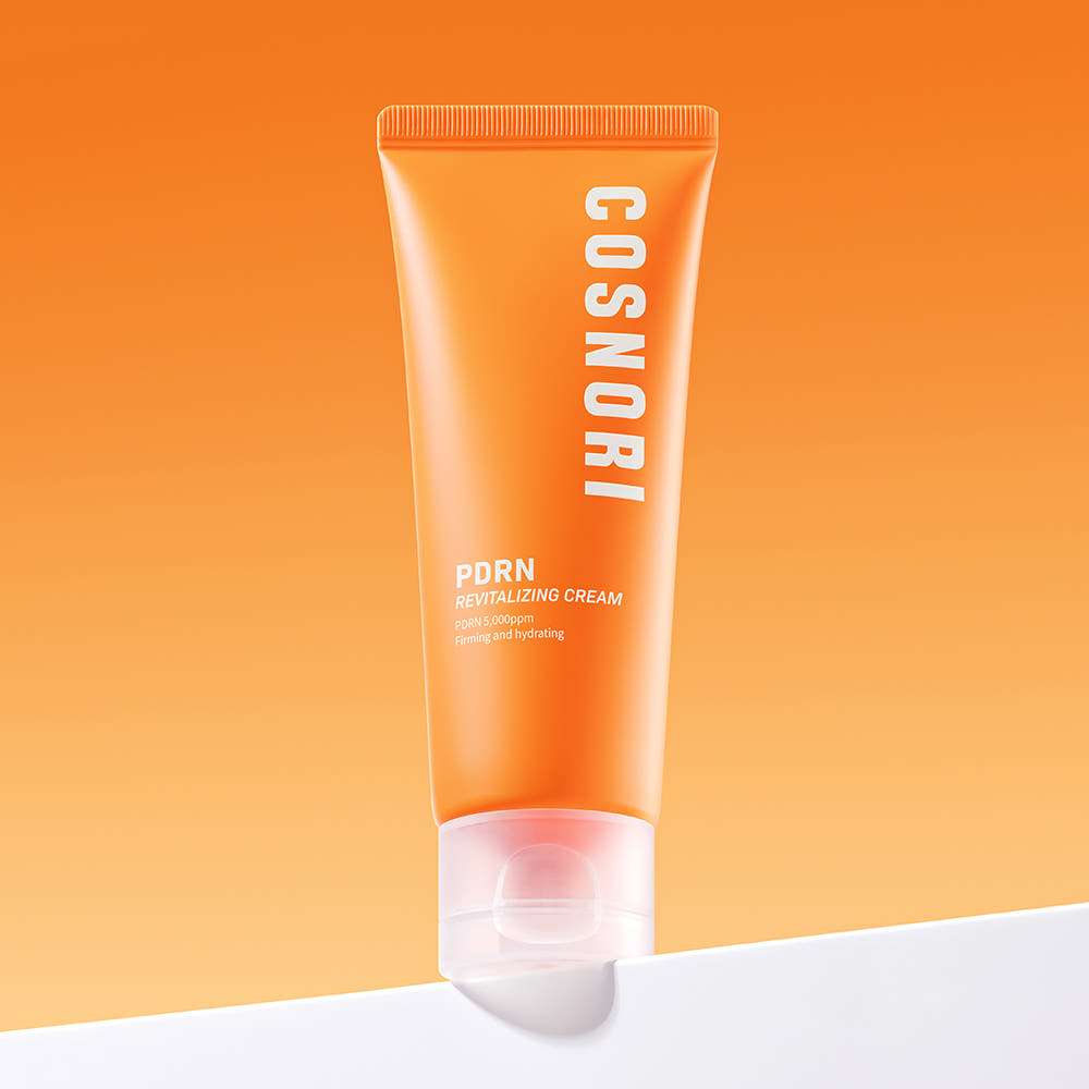 COSNORI PDRN Revitalizing Cream 70ml : tube orange sur fond orange et blanc, produit cosmétique en studio.