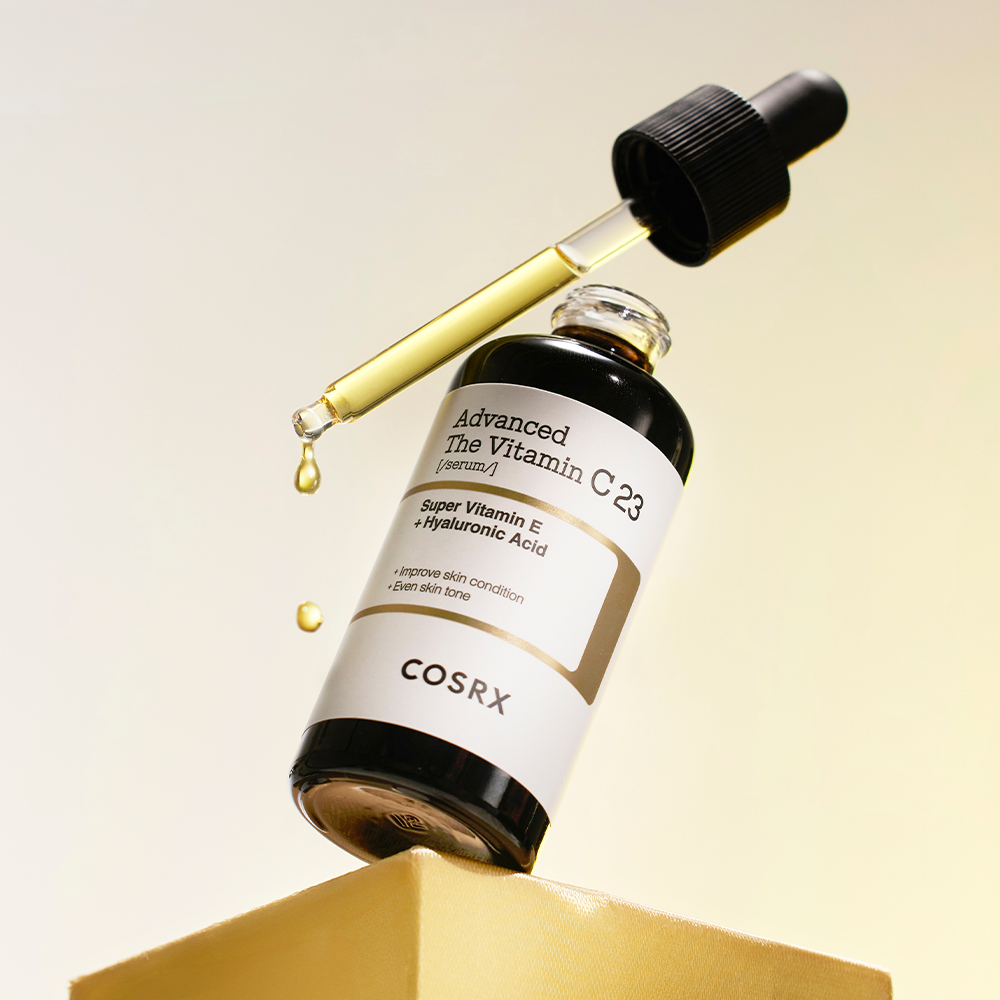 COSRX Advanced The Vitamin C 23 Serum, flacon en verre, marque COSRX, gouttes sur fond beige en lumière douce
