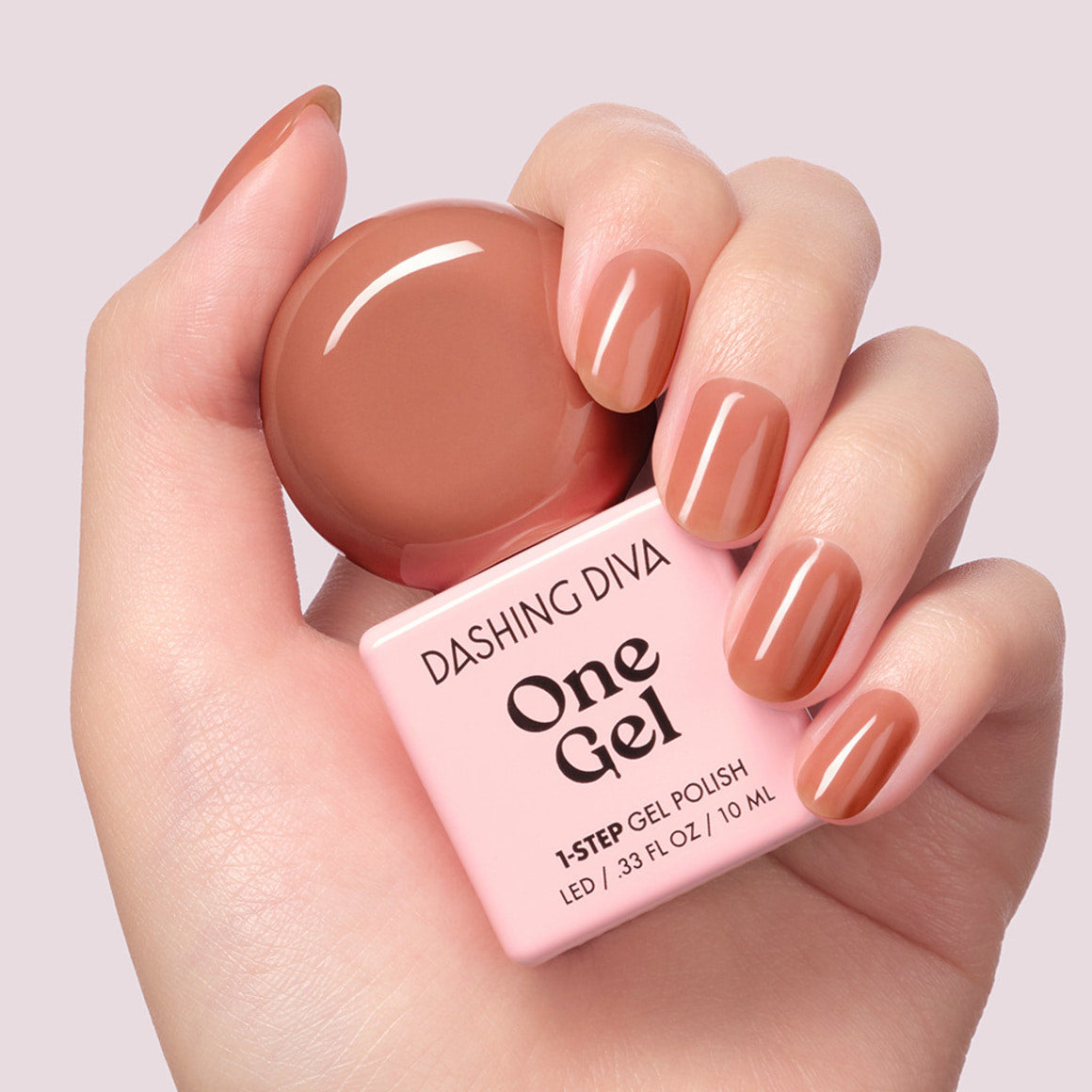 DASHING DIVA One Gel Muted Bear sur ongles, flacon rose en main sur fond clair, marque Dashing Diva