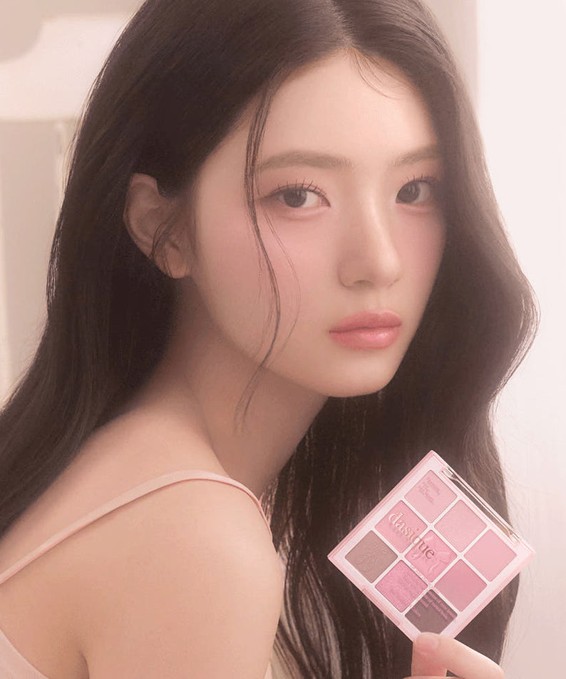 Décris l'image en français : DASIQUE Shadow Palette 8g (#01 - #39) de la marque, palette maquillage tenue par un mannequin.