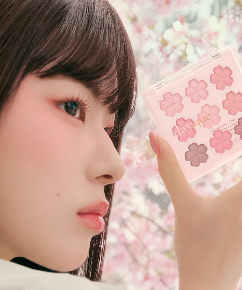 DASIQUE Shadow Palette 8g (#01 - #39), palette maquillage rose tenue près du visage, fleurs en arrière-plan