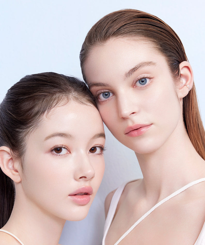 Deux femmes posent avec élégance, mettant en valeur DEAR DAHLIA Sun Breeze Hydro Sun Lotion et son effet éclatant sur la peau.