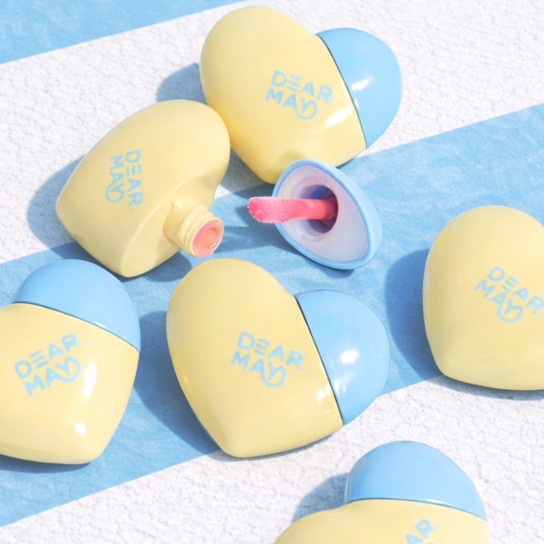 DEAR MAY Mellowpose Light Gloss de DEAR MAY, bonbons jaunes et bleus sur fond bleu clair, packaging visuel