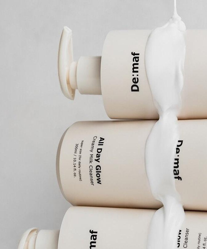 DE:MAF All Day Glow Creamy Milk Cleanser 300ml par De: maf, flacons crème, texture laiteuse sur fond clair.