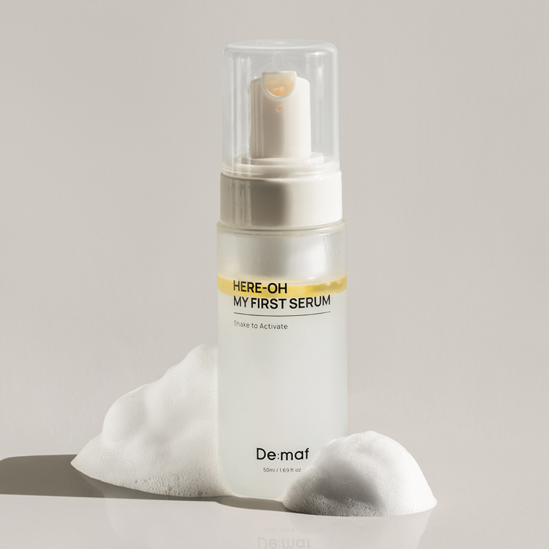 DE:MAF Here-Oh My First Serum 155ml, De maf, sérum en flacon blanc sous sur coussin, fond clair.