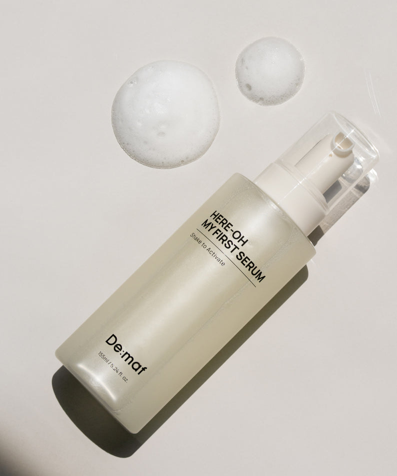 DE:MAF Here-Oh My First Serum 155ml, flacon De.maf sur fond clair avec bulles, contexte cosmétique.