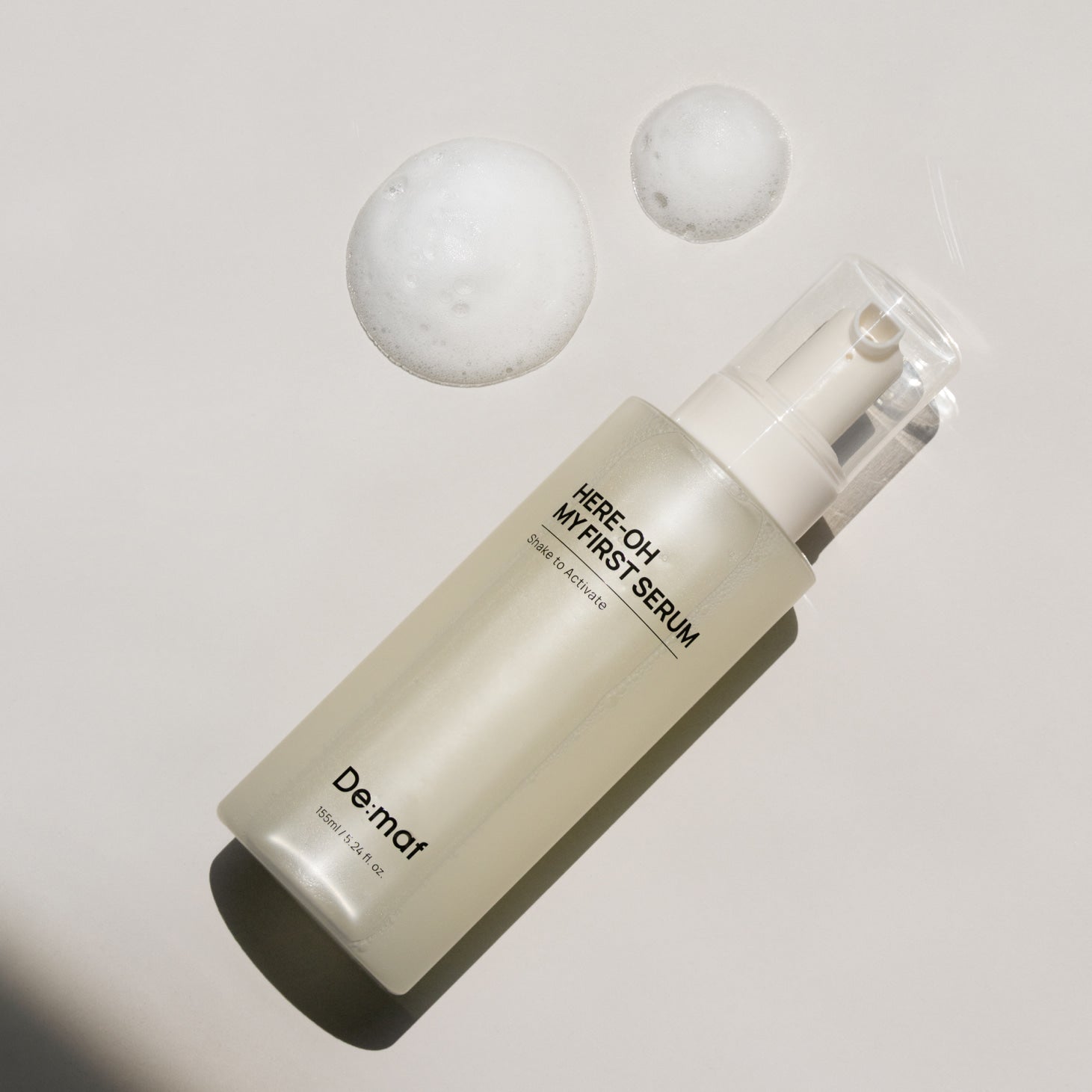 DE:MAF Here-Oh My First Serum 155ml, flacon De.maf sur fond clair avec bulles, contexte cosmétique.