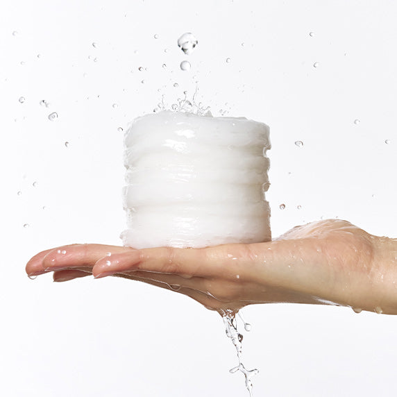 DERMATORY Hyaluronic Acid Moisture Spring Embo Pad Refill 60 sheets, main avec coussin hydratant à l’eau, contexte soin visage.