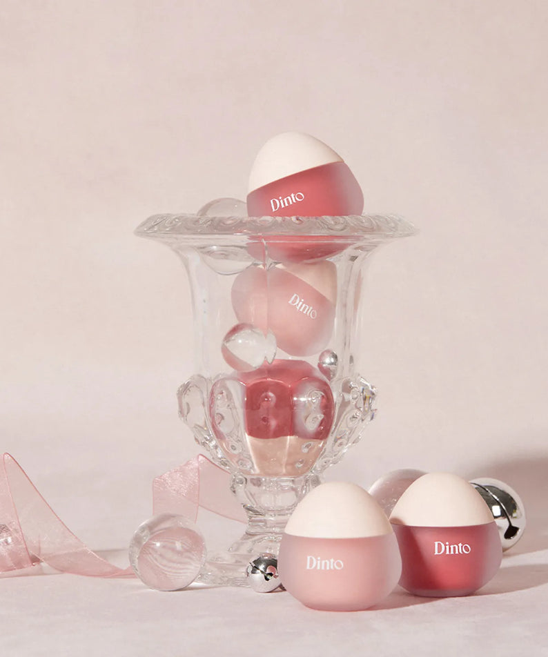 Un présentoir en verre élégant exposant le DINTO Chubby Mochi Jelly Popo Lip Mask, offrant une touche de soin luxueuse.